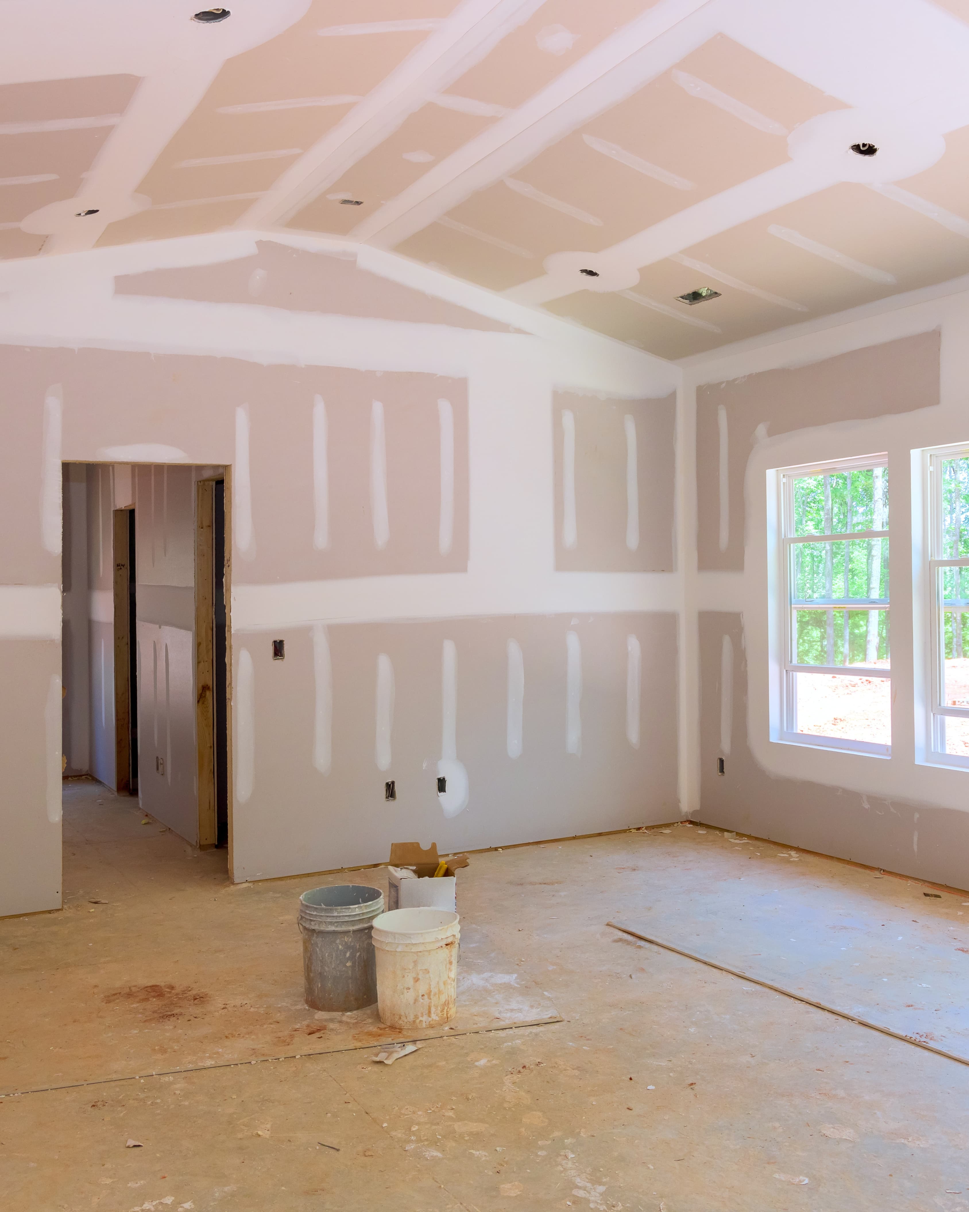 Residential room mid-restoration with fresh drywall and empty floor