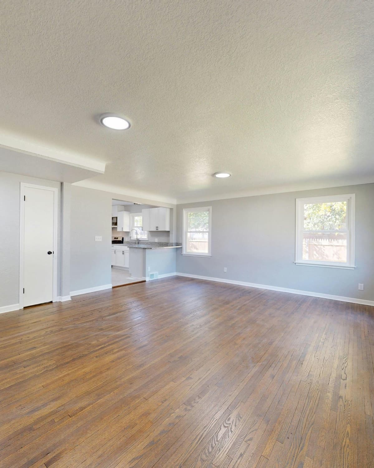 Empty rent-ready living room with refinished hardwood floors